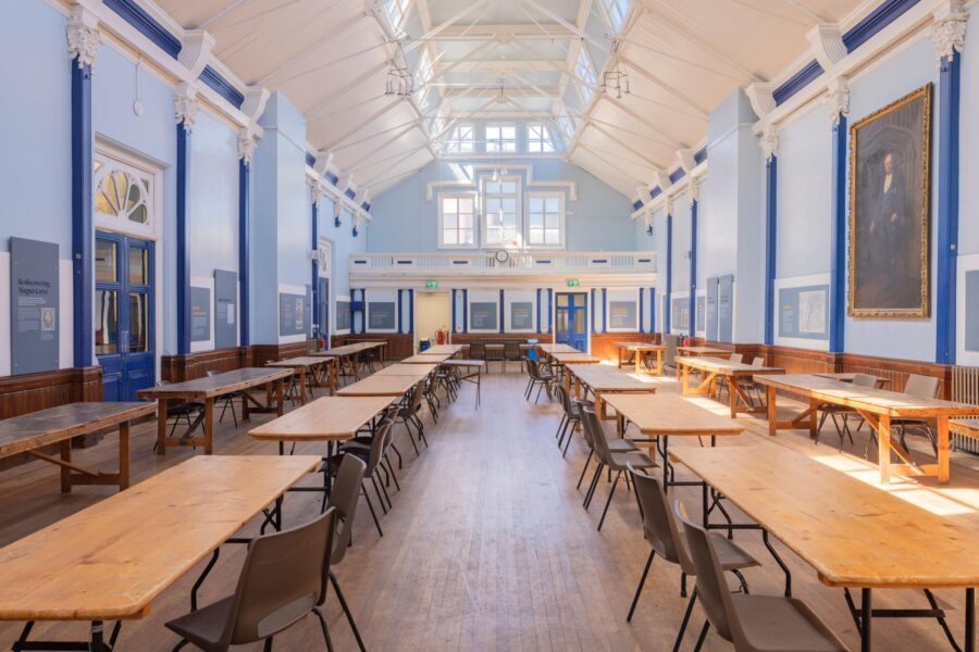 The Corn Exchange at Lewes Town Hall, a high timber-roofed hall with tall windows and pale blue walls, laid out with long trestle tables.